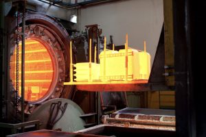Forno per trattamenti termici industriali Vista di un forno industriale con componenti metallici incandescenti durante il trattamento termico.